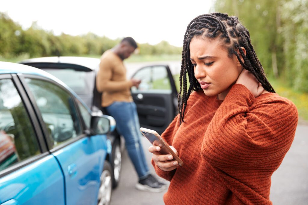 Woman holds her neck as she uses phone to call an Alabama accident lawyer