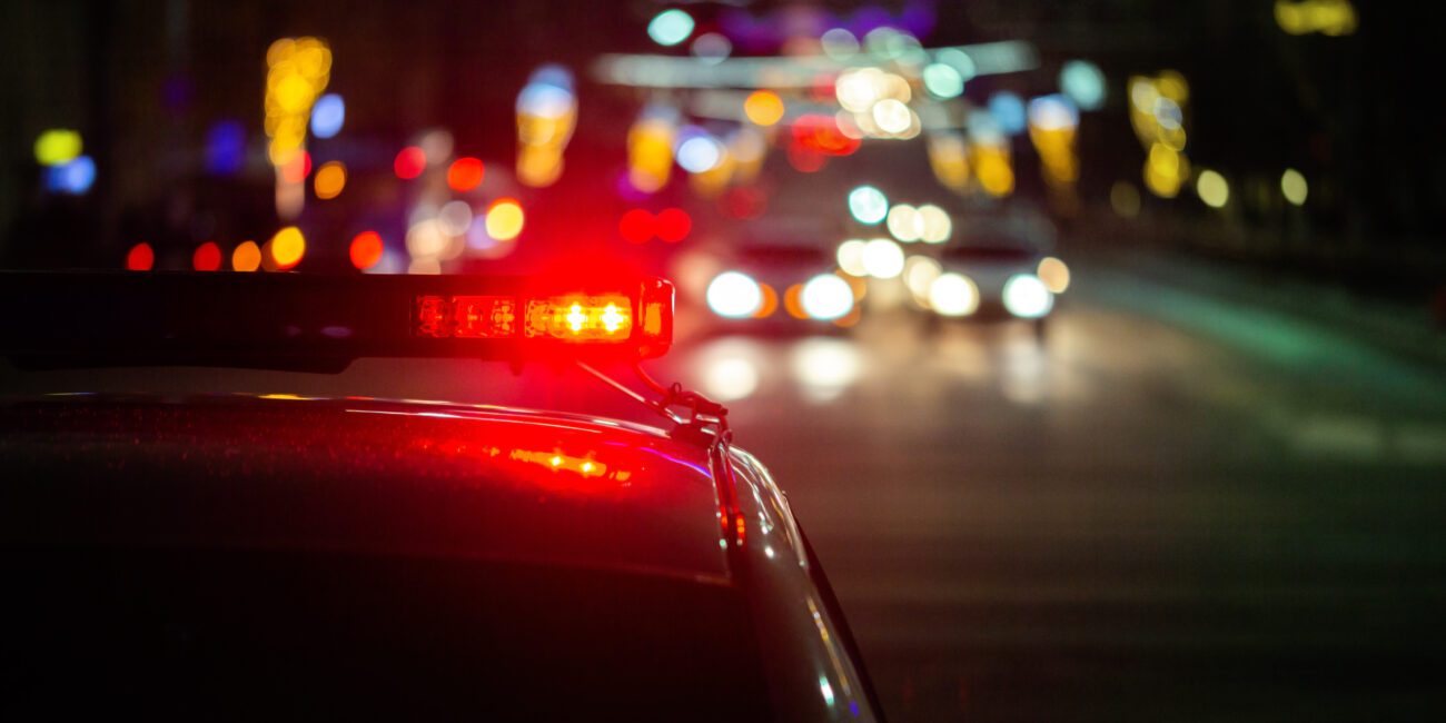 Night scene on highway with police lights in foreground meant to depict importance of having a drunk driving accident lawyer