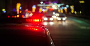 Night scene on highway with police lights in foreground meant to depict importance of having a drunk driving accident lawyer