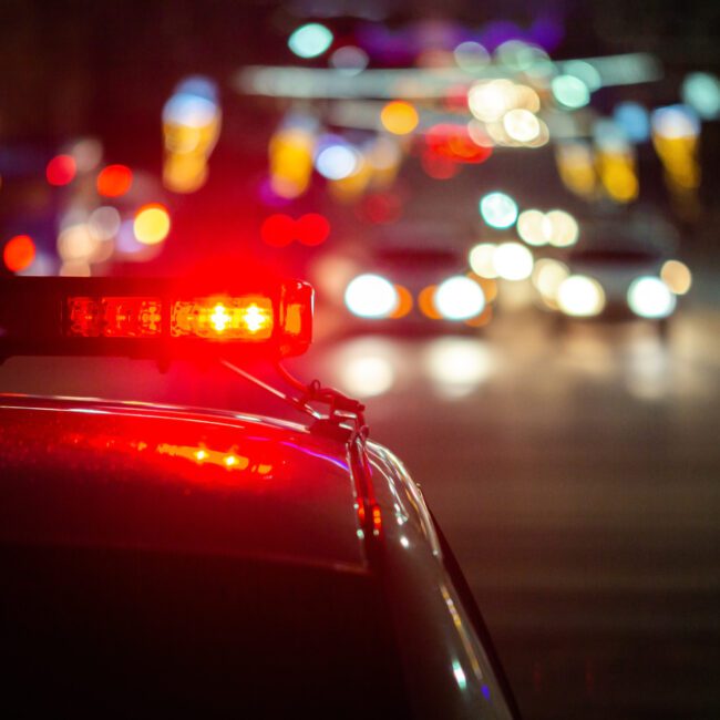 Night scene on highway with police lights in foreground meant to depict importance of having a drunk driving accident lawyer