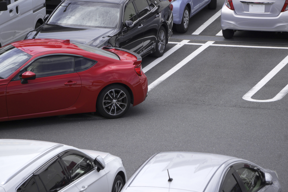 red car backing into parking spot in parking lot